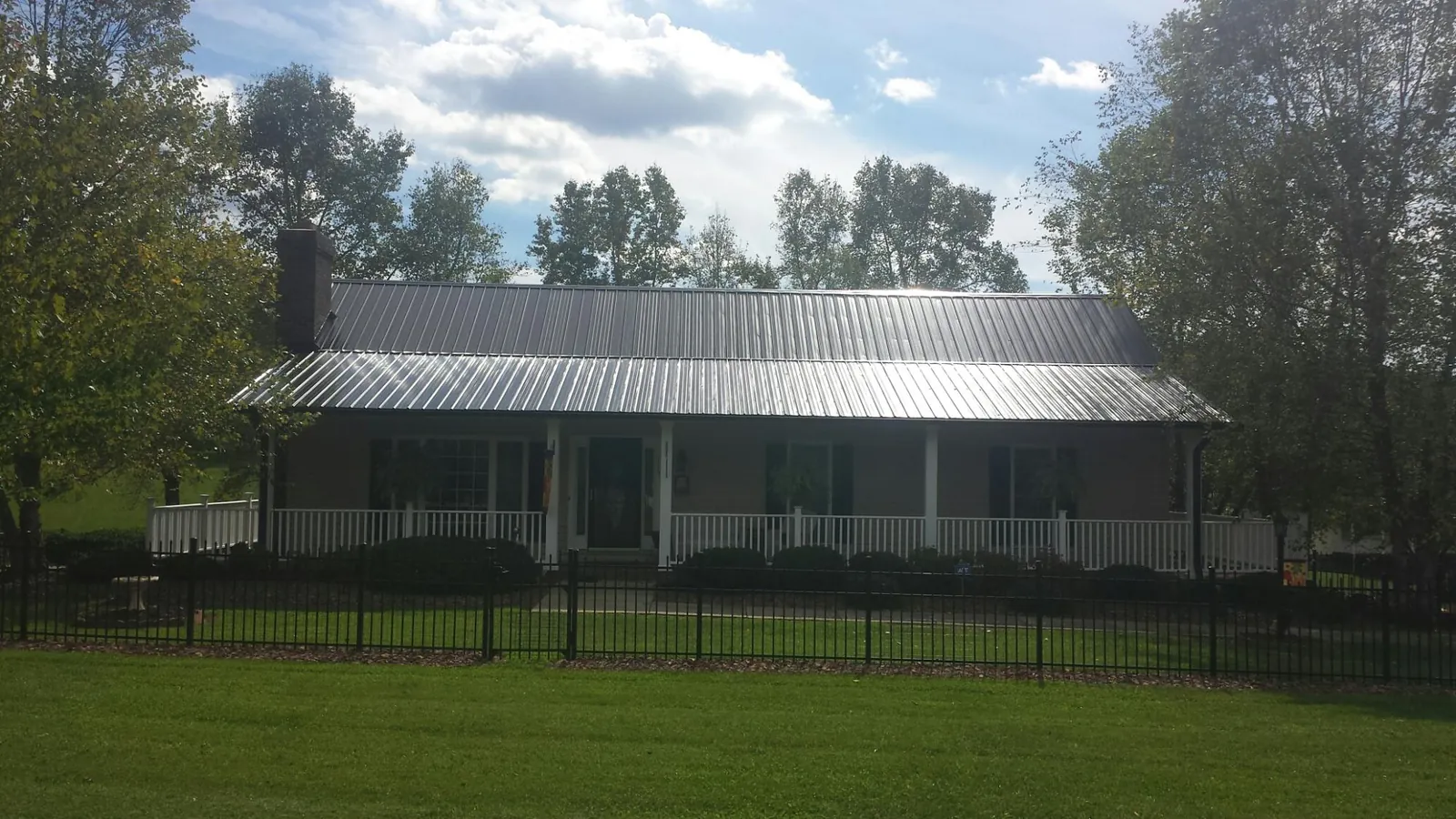 Gray metal roof on a brick ranch with a full width front porch — Gutter Guard Installation work by our crew in Pardeeville