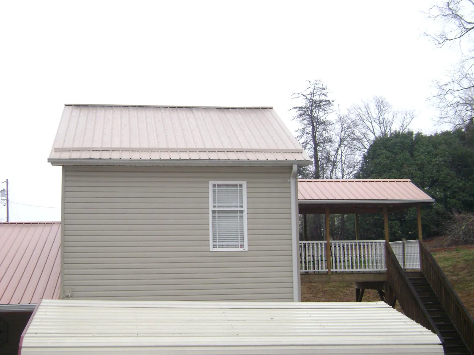 Tan metal roofs on a two story addition and attached porch, from a Roof Replacement job in Pardeeville