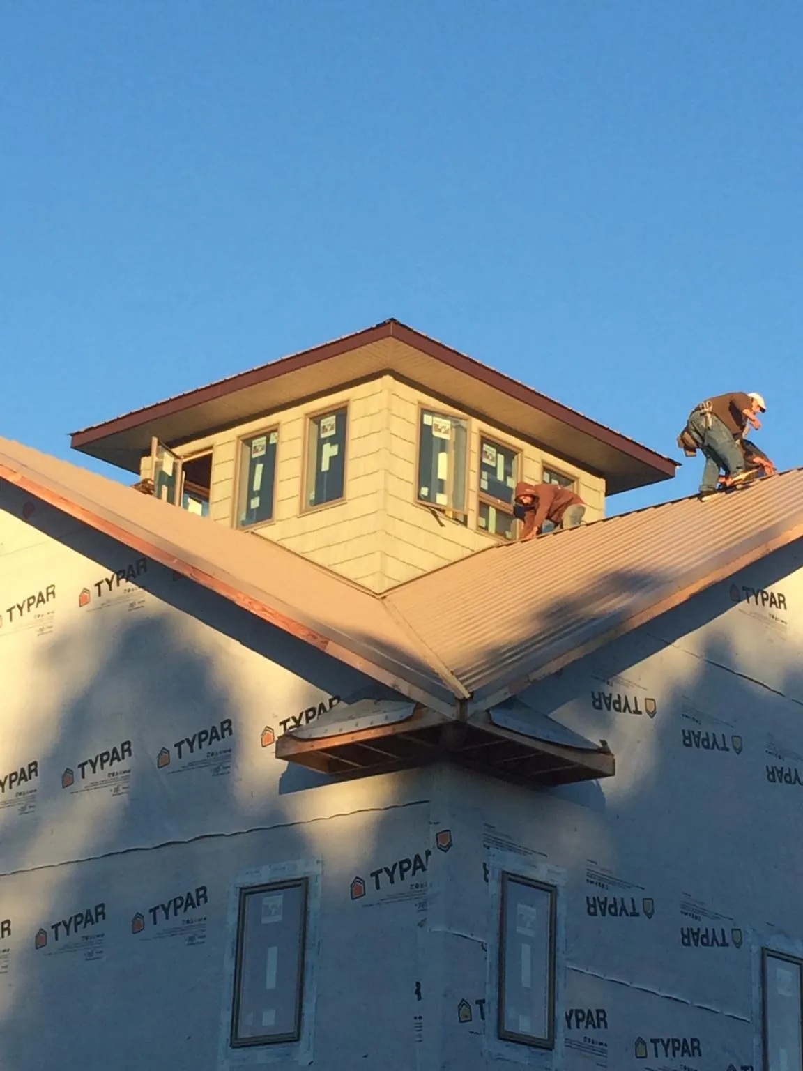 Roofers working around a rooftop cupola on a new metal roof at sunset — Roof Waterproofing in Pardeeville by Roofing Brothers